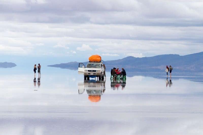 Geländewagen und Menschen auf dem überfluteten Salar de Uuyuni