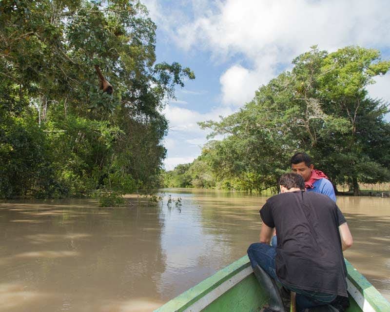 Turista e guia navegando no rio Amazonas em Iquitos, Peru, com árvores ao fundo