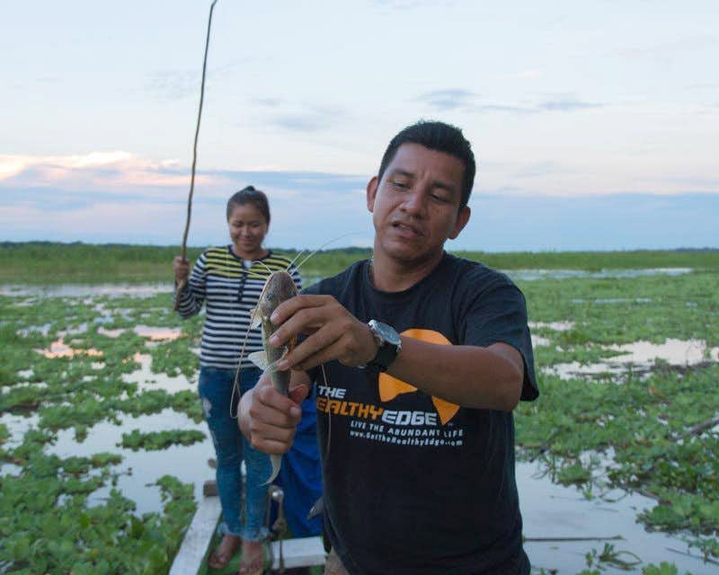 Guia mostrando na câmera uma das piranhas pescadas na selva de iquitos