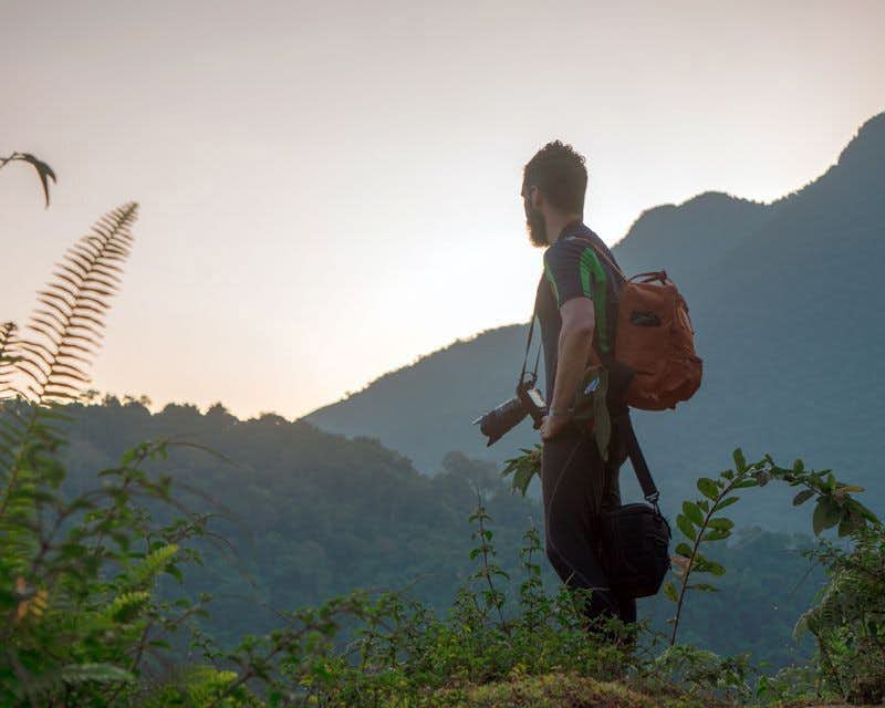 Junge mit Kamera und Bergen im Hintergrund beim Trekking durch die verlorene Stadt in Kolumbien